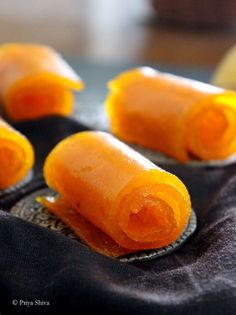 several pieces of orange candy sitting on top of a black cloth covered table next to an orange slice