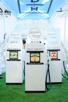 three white gas pumps sitting next to each other on top of green carpeted ground