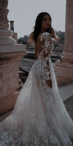 a woman in a white wedding dress posing for the camera with her back to the camera