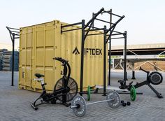 there is a bike and exercise equipment in front of a shipping container on the ground