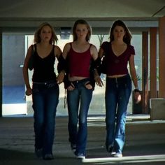 three women walking down the street in jeans