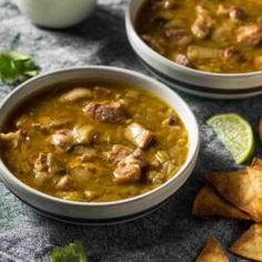 two bowls filled with soup next to some chips