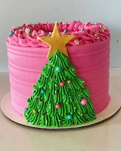 a pink cake with green icing and a christmas tree decoration on it's side