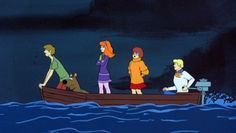 people in a boat on the water at night with one person standing and two others sitting