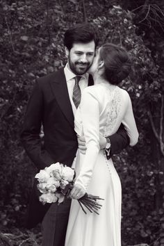 a man in a suit and tie standing next to a woman wearing a wedding dress