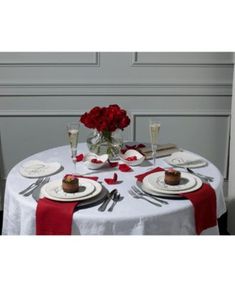 a white table topped with plates covered in red roses