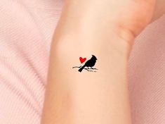 a small bird with a heart on it's back arm, sitting on a branch