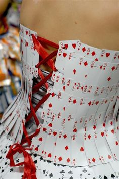 a dress made out of playing cards with red ribbon on the bottom, and an arrow at the waist