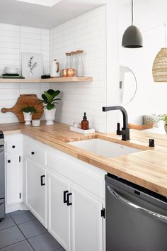 a kitchen with white cabinets and wooden counter tops