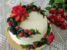 a cake decorated with berries and flowers on a table