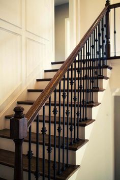 a stair case with wrought iron railing and wood handrail