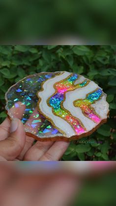 a hand holding a decorated cookie in front of some bushes and plants with holographics on it