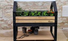 a wooden planter with plants growing in it on a wood platform next to a stone wall