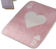 a pink rug with white hearts on it next to a toothbrush and cleaning cloth