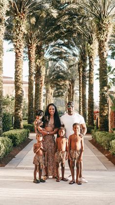 a man and woman standing with two children in front of palm tree lined walkways