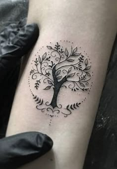 a tree tattoo on the arm with leaves and branches around it, in black ink