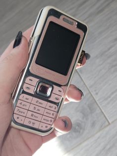 a woman's hand holding an old cell phone in her left hand, on the floor