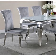 a glass dining table with four grey chairs