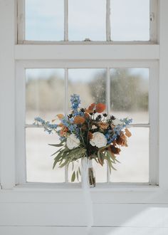 a bouquet of flowers sitting on top of a window sill in front of a white wall