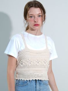 a young woman is standing in front of a white wall wearing a crochet top