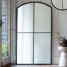 a white toilet sitting next to a tall mirror in a room with wooden floors and walls