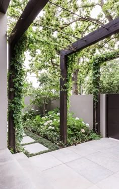 an outdoor garden with white flowers and greenery on the walls, surrounded by stone walkways