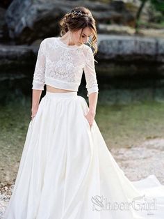 a woman in a white wedding dress standing next to a river with her hands on her hips