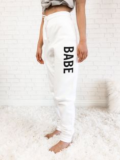 Custom text joggers are a cute outfit for the future bride to wear during her winter wedding planning. These soft white fleece joggers are perfect to keep warm while lounging around. Each soft jogger comes with an elastic waistband, cuffed ribbed ankles, 2 front pockets, and 1 pocket in the back. Choose to personalize them in your choice of script or block custom text. Personalization is on the LEFT leg only. DETAILS Listing is for 1 White Jogger Pant. NO RETURNS OR EXCHANGES ON SHIRTS/CLOTHING White Athleisure Bottoms With Letter Print, Athleisure White Bottoms With Letter Print, White Letter Print Joggers Athleisure, White Letter Print Sweatpants In Athleisure Style, White Letter Print Athleisure Sweatpants, White Sporty Joggers With Letter Print, White Athleisure Sweatpants With Letter Print, Sporty White Joggers With Letter Print, White Letter Print Casual Joggers