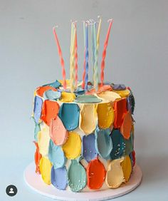 a multicolored birthday cake with candles on it