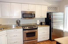 a kitchen with white cabinets and stainless steel appliances, including a stove, refrigerator, microwave, dishwasher and coffee maker