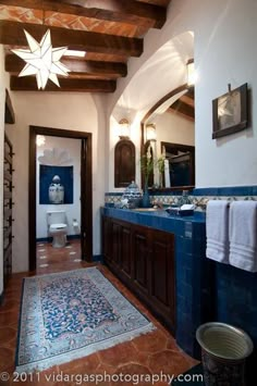 a large bathroom with blue tile and wood accents on the walls, along with an area rug