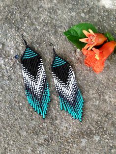 two pairs of blue and white beaded earrings next to a flower on the ground