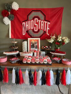 the dessert table is decorated with red, white and black tassels