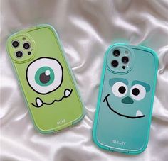 two cell phones with faces on them laying on a white sheet, one is green and the other is blue