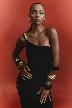 a woman in a black dress and gold bracelets on the cover of a magazine