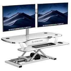 two computer monitors sitting on top of a desk