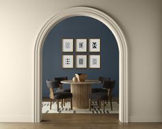 a dining room with blue walls and wooden flooring is seen through an arched doorway