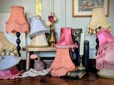 several lamps are lined up on a table in front of books and other decorative items