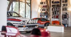 two cars parked in a garage next to bookshelves and shelves full of books