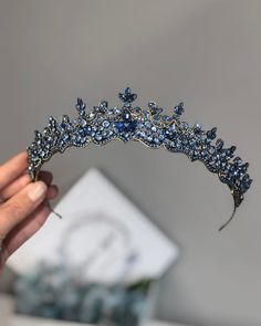 a tiara is being held by a woman's hand with blue crystals on it