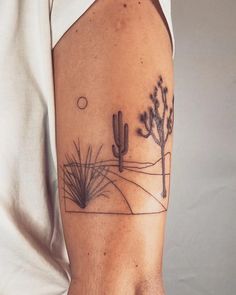 a person with a tattoo on their arm that has a desert scene and cactus trees