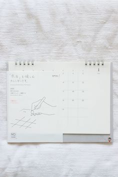 a calendar with a hand drawn on the front and side of it, sitting on top of a white sheet