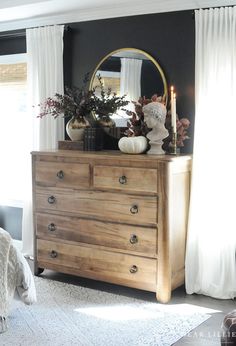 a bedroom with a dresser, mirror and vases on top of it in front of a window