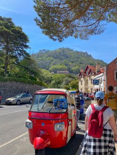 two people are walking down the street next to an old vw bus and small van