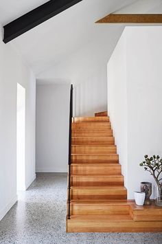 the stairs are made of wood and have black railings on each side, along with white walls