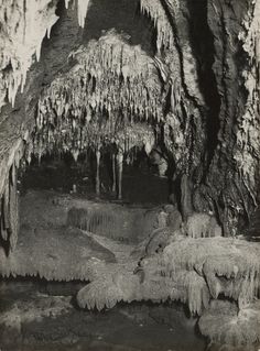 an old black and white photo of icicles hanging from the side of a cave