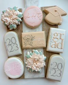 decorated cookies on a wooden board with flowers and graduation caps in the middle, along with congratulations messages