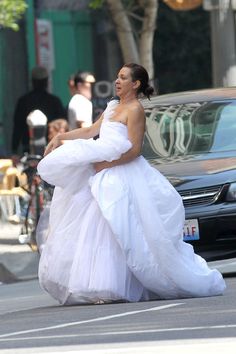 a woman in a white dress is walking down the street