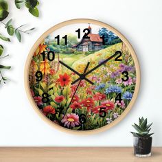 a clock with flowers painted on it next to a potted plant