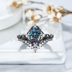 an opal colored ring sits on top of a white plate with flowers in the background